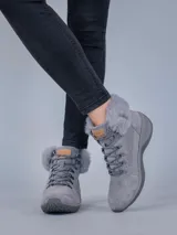 Botas de estilo montañés color gris, confeccionadas en cuero y poliéster. Presentan cuello con forro de piel sintética, ajuste mediante cordones con ganchos metálicos y suela de goma con tecnología Spinal Flex para mayor confort.