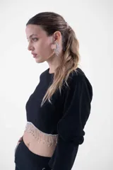 Top negro corto con mangas largas, cuello redondo y detalle de flecos de strass colgantes en el ruedo.