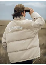 Campera puffer color nude (beige claro) con diseño acolchado. La parte superior de los hombros y el cuello son de pana acanalada. Presenta un bordado en la espalda con la palabra "Chingona" en tipografía gótica blanca. Posee tiras regulables en la cintura.