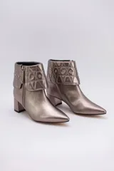 Botas cortas color peltre con taco cuadrado, capellada de cuero y cuello con diseño capitoné y apliques brillantes.