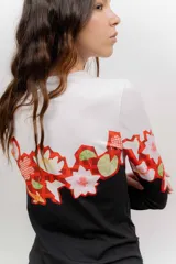 Remera de manga larga de algodón elastizado, con cuello redondo y estampado geométrico floral en tonos blanco, amarillo, verde y rosado.