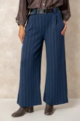 Pantalón de corte ancho y tiro alto, confeccionado en tejido azul marino con finas rayas verticales de hilo de lurex plateado. Presenta cintura con pasacintos y se incluye un cinturón negro con hebilla metálica.