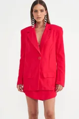 Blazer fucsia con solapa de muesca, hombreras marcadas y un único botón frontal. Incluye dos bolsillos de parche en la parte delantera.