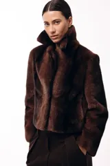 Tapado corto de piel sintética en color marrón chocolate, con cuello solapa amplio y cierre frontal oculto. Presenta una silueta estructurada y elegante.