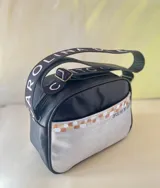 Bandolera de cuero negro y plateado con arte pintado a mano, perteneciente a la línea Ottenta de Carolina De Cunto. Cuenta con bolsillo frontal exterior, cierre superior con cremallera, forro interior con bolsillo y correa regulable con el logo de la marca.
