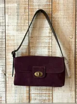 Cartera tipo baguette de cuero con textura efecto cocodrilo, color bordó. Presenta una solapa frontal con cierre de broche metálico en tono bronce y una correa ajustable para llevar al hombro.