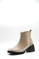 Bota corta de cuero en tono beige, con diseño bicolor que presenta un panel lateral en un tono más claro. Cuenta con un taco cuadrado negro de altura media y cierre lateral interno.