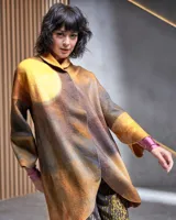 Tapado de lana merino afieltrada color ocre con teñido artesanal tie dye en forma de luna, cierre cruzado asimétrico con broches, cuello alto y bolsillos laterales.