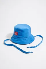 Gorro tipo bucket de tejido técnico color azul vibrante, con ala flexible y cordón ajustable para sujetar bajo la barbilla. Presenta un parche rectangular con el logo de la marca en la parte frontal.