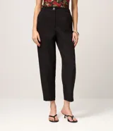 Pantalón carrot en crepé negro, de cintura alta, corte holgado en las caderas que se estrecha hacia los tobillos, con bolsillos laterales.