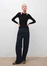 Camiseta de canalé color negro, de manga larga y diseño entallado con cuello halter y aberturas en los hombros.