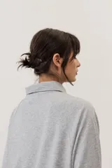 Buzo celeste de manga larga con cuello polo y cierre frontal de botones. Presenta un parche marrón bordado en el pecho.