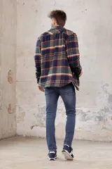 Sobrecamisa de corte holgado con diseño a cuadros en tonos azul marino y marrón, confeccionada con forro interior de corderito sintético, cuello clásico, cierre frontal de botones y bolsillos en el pecho.