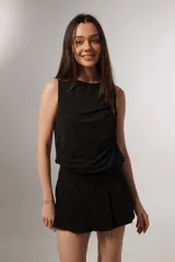 Musculosa negra sin mangas con cuello a la base y diseño holgado con frunces laterales.