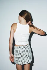 Minifalda blanca con lentejuelas negras formando un patrón geométrico.