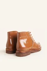 Bota acordonada de cuero vacuno con acabado charol color suela, con suela de goma tipo crepe y costuras reforzadas.