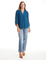Blusa de color blanco con escote en V y cuello mao. Presenta mangas largas con presilla y botón para regular el largo, y un corte holgado con ruedo redondeado.