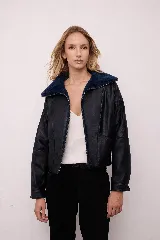 Chaqueta estilo bomber de cuero vacuno con diseño bicolor, presentando cuerpo en tono oscuro y cuello de corderito en contraste. Posee cierre frontal completo, mangas largas y corte holgado de inspiración retro.