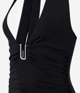 Vestido midi de color negro con escote halter y detalle metálico en el busto. Presenta fruncidos laterales que realzan la silueta y un diseño elegante y ajustado.