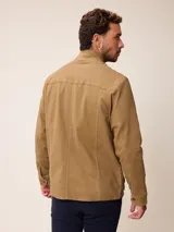 Campera de estilo safari en color azul marino, confeccionada en algodón. Presenta cuello alto, cierre frontal con cremallera y cuatro bolsillos delanteros con solapa y botones metálicos.