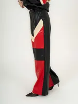 Pantalón de cuero sintético negro con paneles en rojo y beige.