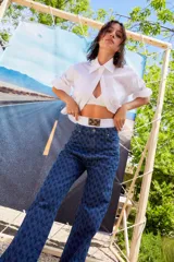 Jean de tiro bajo y corte oversize, confeccionado en denim azul con monograma grabado a láser en toda la prenda. Presenta doble botón metálico en la cintura y diseño de cinco bolsillos.
