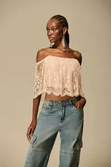 Top cropped de encaje floral color nude con diseño off-shoulder y mangas cortas holgadas.