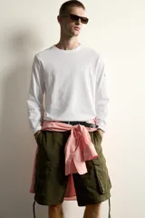Camiseta de manga larga con cuello redondo y corte relajado. Presenta un pequeño bolsillo tipo plastrón con solapa en la manga izquierda.