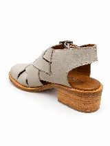 Sandalias cerradas de cuero color gris claro, con diseño de tiras anchas entrelazadas, hebillas metálicas laterales y suela plana de madera.