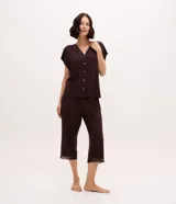 Pijama capri Lov confeccionado en poliéster y elastano, color marrón, compuesto por una blusa de manga corta con escote en V y botones frontales, y un pantalón capri con cintura elástica. Ambos detalles presentan aplicaciones de encaje.