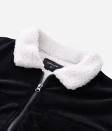 Campera de pana negra con cuello de sherpa blanco, cierre frontal por cremallera y bolsillos delanteros con solapa y botón. Presenta forro interno de sherpa para mayor calidez.