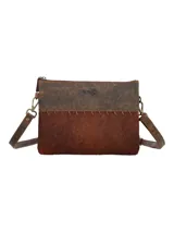 Cartera tipo bandolera de diseño rectangular, confeccionada en una combinación de cuero liso en la parte superior y cuero con pelo en la parte inferior, unidos por costuras decorativas visibles. Cuenta con correa ajustable y extraíble, cierre superior de cremallera y herrajes metálicos en tono bronce envejecido.