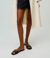 Sandalia mule plana de cuero color negro, con diseño minimalista, capellada ancha y punta cuadrada.