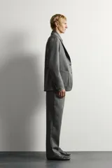 Pantalón de traje gris de corte relaxed fit, confeccionado en pura lana, con bolsillos laterales, bolsillos traseros de doble vivo y raya marcada en las piernas.