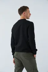 Buzo negro de felpa con cuello redondo, puños y mangas largas. Presenta un estampado con la frase "break the limits" y logo en goma.