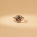 Anillo tipo sello con diseño circular grabado en relieve, fabricado en plata 925 con detalles en oro 9k.