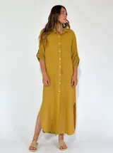 Vestido camisero largo color mostaza, con cuello clásico, abotonadura frontal completa, mangas 3/4 con puños y aberturas laterales en el ruedo.