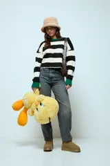 Sweater de punto con diseño de rayas horizontales en blanco y negro, cuello redondo y puños en color verde contrastante.