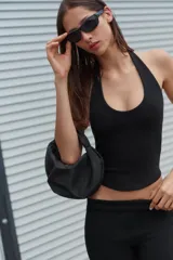 Bolso de mano negro con cuerpo cubierto de apliques brillantes, diseño estructurado con asa superior integrada y cierre principal. Incluye bolsillo interior con cremallera y cadena para usar como bandolera.