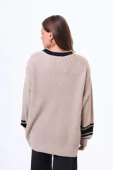 Sweater de punto color marrón con cuello redondo, puños y cuello con detalles de rayas blancas en contraste. De corte holgado y manga larga.