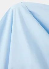 Blusa de algodón celeste con diseño asimétrico de un solo hombro, detalles fruncidos y manga larga.