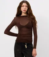 Blusa de manga larga con transparencia, confeccionada en viscosa y elastano. Presenta un diseño ajustado al cuerpo, cuello redondo y textura sutil, ideal para usar en capas.