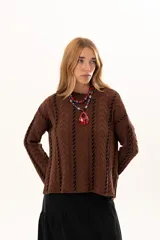 Buzo de tejido de punto color chocolate con diseño de trenzas verticales y detalles de costuras en contraste color negro. Presenta cuello redondo, mangas largas con terminación acampanada y aberturas laterales en el ruedo.