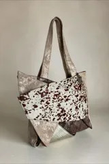 Cartera de cuero combinada en tonos beige, marrón y detalles con estampado animal print tipo vaqueta, con doble asa de hombro y diseño estructurado.
