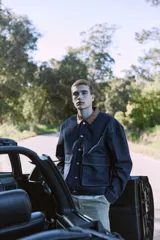 Campera de denim azul oscuro con cuello clásico marrón, cierre frontal con botones metálicos, bolsillos delanteros con solapa y puños con botones. Confeccionada en tejido denim resistente con estructura de sarga.