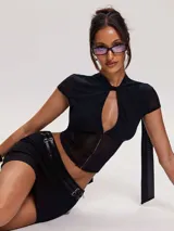 Top de tul negro con diseño tipo corset, mangas cortas, cuello alto con lazo frontal y cierre de ganchos metálicos en el frente.