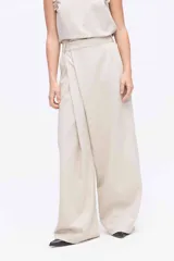 Pantalón beige de pierna amplia con detalle de cruce delantero, tiro medio y caída suave y elegante.