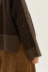 Sweater de tejido de punto en color beige, con mangas largas que presentan detalles de textura en relieve y paneles laterales en tono gris. Confeccionado en lana italiana, cuenta con puños acanalados y detalles en lurex.