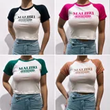 Remera corta blanca con mangas raglán de diferentes colores y estampado frontal con la leyenda "Malibu California A Beautiful Place".