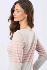 Remera de manga larga con cuello redondo y cierre frontal parcial con botones. Presenta un diseño de rayas horizontales en tonos pastel sobre una base beige, con aberturas laterales en el ruedo.